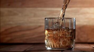Whiskey is poured into a glass with ice. Filmed on a high-speed camera at 1000 fps. High quality FullHD footage video