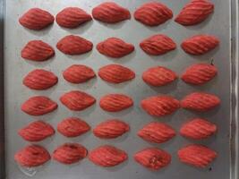 A Baking Sheet with Rows of Red Shell-Shaped Cookies. photo