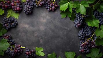 Fresh dark grapes with green leaves arranged on a textured dark background, creating a rustic and organic composition photo