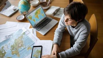 A teenager looking at a world map on a digital device planning a virtual geography project with research materials spread out on a table photo