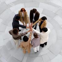 Diverse group stands in a circle, hands clasped together, unified photo