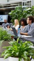 Diverse group of people working at a modern office table surrounded by greenery photo