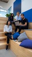 Four people sitting on a wooden bench in an office photo