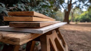 Wooden planks stacked on a workbench outdoors. Stacked lumber resting on a rustic worktable in a natural setting photo