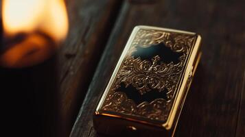 A gold lighter sitting on a wooden table next to a candle photo