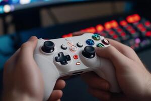 A person holding a white game controller in front of a computer screen photo