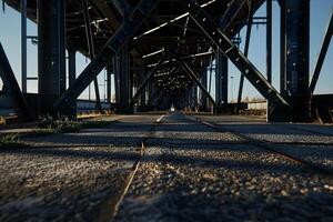 Perspective view of metal bridge's underside. Concrete path stretches into distance photo
