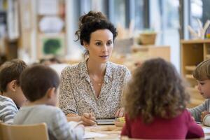 Teacher and preschoolers at a table, engaged in activity photo