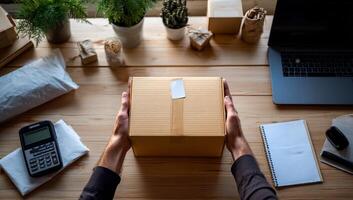 Hands holding a cardboard box, workspace photo