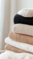 Soft woolen sweaters neatly folded, stacking neutral colors representing seasonal comfort and cozy winter layers photo