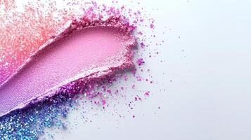 Crushed makeup palette revealing shimmering eyeshadow colors blending into gradient texture against soft white surface photo