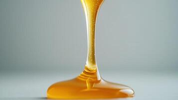 Golden honey rustic from sticky wooden dipper, forming cascading amber stream over soft blue backdrop photo
