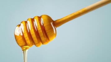 Golden honey cascading from blue wooden dipper, forming sticky amber stream over soft rustic backdrop photo
