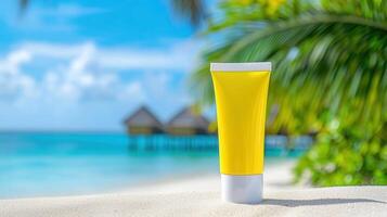 Yellow sunscreen bottle standing on white sand beach with tropical palm leaves and turquoise background in sea photo
