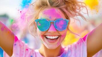 Young happy woman with colorful powder on her face and sunglasses, enjoying the holi color festival with a cheerful smile photo