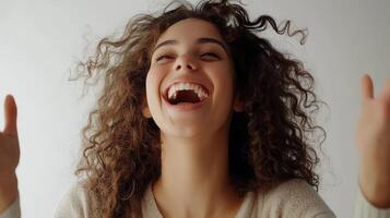 A joyful happiness young with emotion woman curly hair, grinning widely and raising her hands in excitement, framed by a white background photo