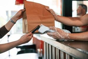 Payment ,by,, using terminal, order is ready.. Man is serving delicious street food photo