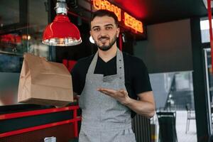 Order in ,package is ready. Man is serving delicious street food photo
