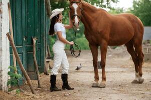 Woman is in ,,hat, side view. With a horse outdoors photo