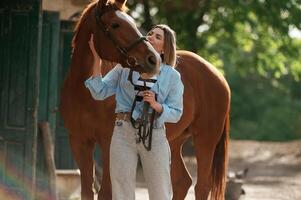 Enjoying, and standing with an animal. Young beautiful woman is with a horse outdoors photo