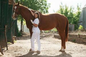 Making, an injection by syringe. Female vet is with horse outdoors at the farm at daytime photo