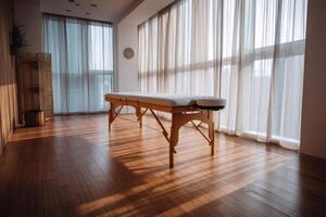 Empty massage table stands in room with sunlight streaming through window photo