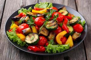 Grilled vegetables decorating a black plate with lettuce on a wooden table photo