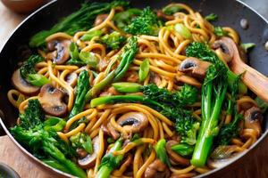 Egg noodles stir fry with mushrooms and broccolini in a pan photo