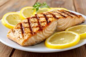 Grilled salmon fillet with lemon slices on white plate photo
