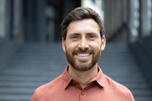 A cheerful man with a warm smile poses in front of a building with a stone staircase, radiating positivity. photo