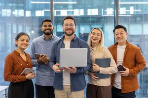 A diverse team of colleagues smiles with joy and confidence while looking at the camera in the office. Collaboration. photo