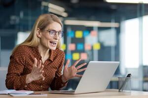 Successful businesswoman at workplace celebrating successful achievement results. Woman received online notification of winning and triumphant results of new project. photo