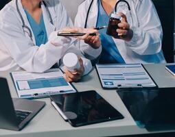 Two doctors are looking at a tablet computer and a bottle photo