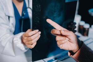 A doctor pointing to a black and white image on a screen photo