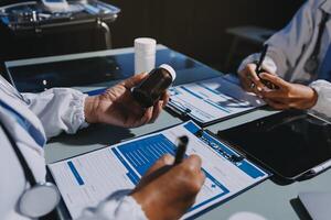 Two doctors are working on paperwork while sitting at a table photo