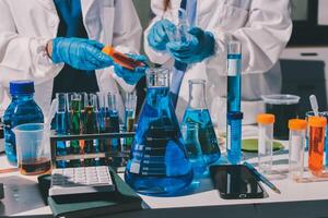 Two people in lab coats and gloves are working on a table with various chemicals photo