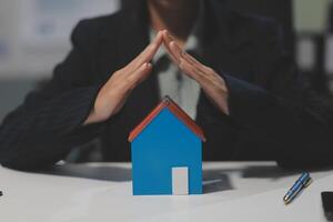 A woman in business suit is holding a house model in her hands photo