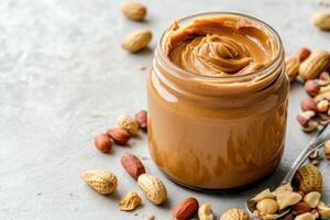 Delicious peanut butter spread in a jar with scattered peanuts photo