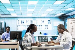 Black medical staff and patient discussing diagnostic feedback and records, emphasizing expertise and data driven decision making. Young adult listens to professional advice for wellness. photo