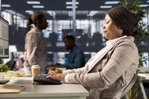 African american female administrator focused on business operations, reviewing a project brief in order to ensure progress and meet objectives. Looking for solutions and resource allocation plans. photo