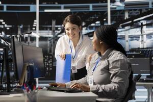 Teamworking colleagues in server hub pleased after successful operations. Happy data center engineering team checking infrastructure health report showing stable performance indicators photo