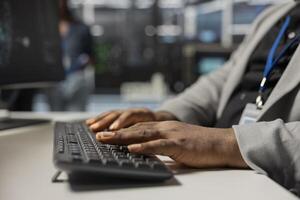 Close up of data center technician typing on keyboard, inspecting gear, doing maintenance tasks. Server farm employee coding on PC, conducting system checks to ensure operational stability photo