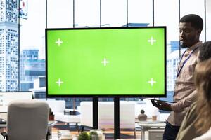 Diverse group of startup employees looking at green screen on an interactive board, meeting to discuss ideas and details to ensure organizational progress. Forecast affiliates in office. photo
