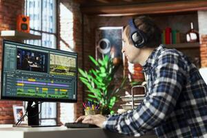 editor analyzing film montage on computer screen before editing color grading and lighting in creative home office. Post production studio employee working with raw footage on PC photo