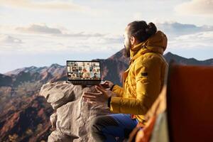 Entrepreneur uses high speed internet connection on mountain top, enjoying the call with a scenic landscape. Young hiker having an internet dependency and being workaholic. photo