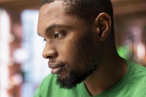 Man having detached apathy facial expression while at home, not caring. Apathetic African american having disinterested indifferent mood while in apartment, close up shot photo