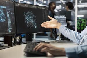 Close up of programmer looking at computer monitor in data center, managing server virtualization, running scripts. Worker using programming language on PC screen in server farm photo