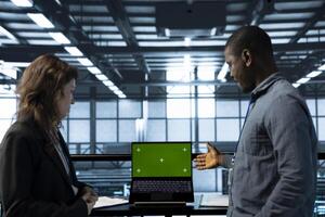 Engineers in data center using green screen mockup laptop to develop disaster recovery plans. IT experts in server farm testing failover scenarios on chroma key device, protecting data photo