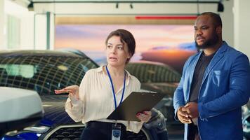 Saleswoman in dealership negotiating price and extra car features to help solidify deal, earning commission bonuses on every sale. Agent persuading hesitant customer to buy vehicle, camera A photo