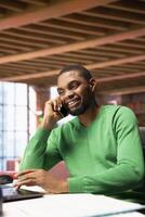 Smiling man at home having friendly conversation with friend over phone call on smartphone. African american person having fun catching up with mate in telephone call, having lively discussion photo
